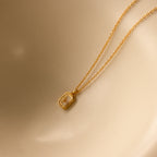 North Star Diamond Necklace featuring a rectangular crystal pendant, elegantly displayed on a smooth beige surface.