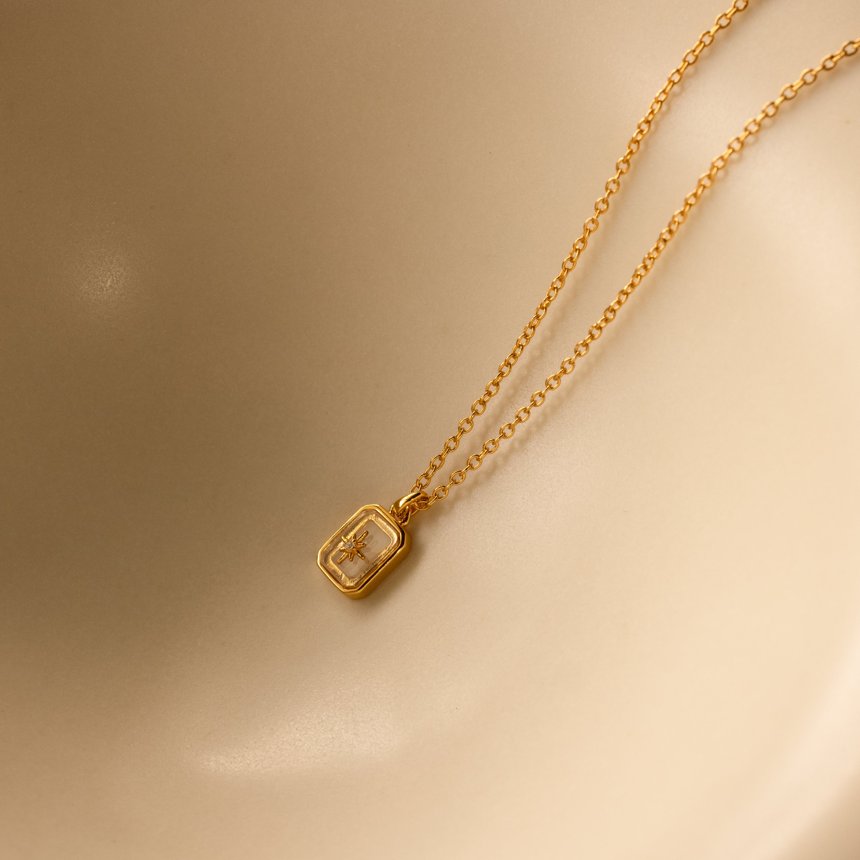 North Star Diamond Necklace featuring a rectangular crystal pendant, elegantly displayed on a smooth beige surface.