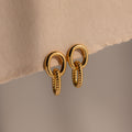 Twisted Link Earrings in 18K Gold showcase an oval, textured chain design against a soft beige background—ideal for those who love modern and elegant jewelry.