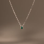 Multiple Teardrop Birthstone Necklace featuring a delicate silver chain and small green pendant, shown on a plain brown background—ideal as personalized jewelry or a meaningful gift.