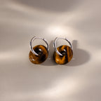Tiger's Eye Duo Hoops in White Gold, featuring brown circular stone charms, are displayed on a neutral background with soft shadows.