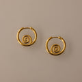 The Spiral Swirl Hoops in 18K Gold feature intricate spiral designs, making them perfect boho vacation jewelry, shown against a plain beige background.