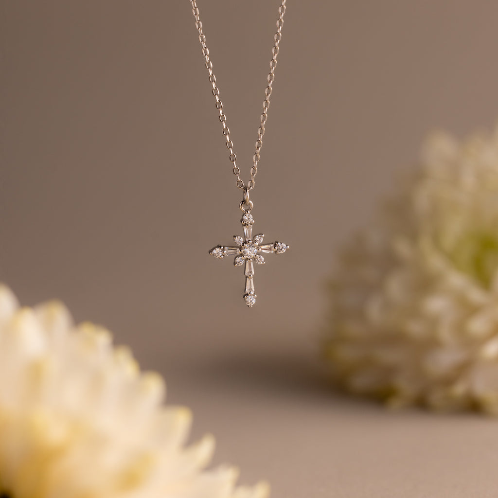 Vintage Diamond Cross Necklace in Silver featuring sparkling diamond accents as a cross pendant, set against a soft white floral background.