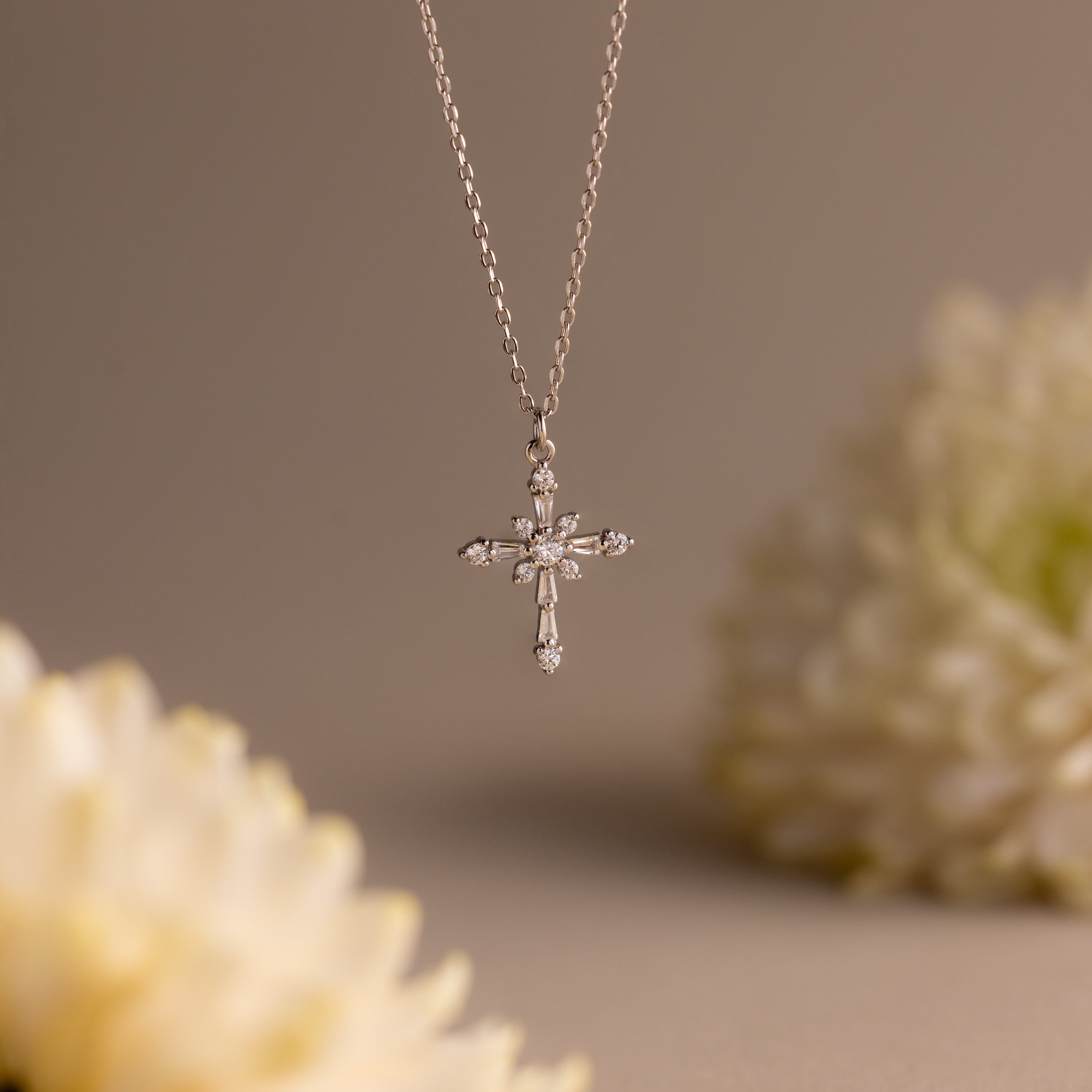 Vintage Diamond Cross Necklace in Silver featuring sparkling diamond accents as a cross pendant, set against a soft white floral background.