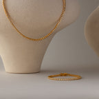 The Diamond Bezel Tennis Necklace & Bracelet Set in 18K Gold is elegantly displayed on a bust and neutral background, highlighting the beauty of this diamond jewelry duo.