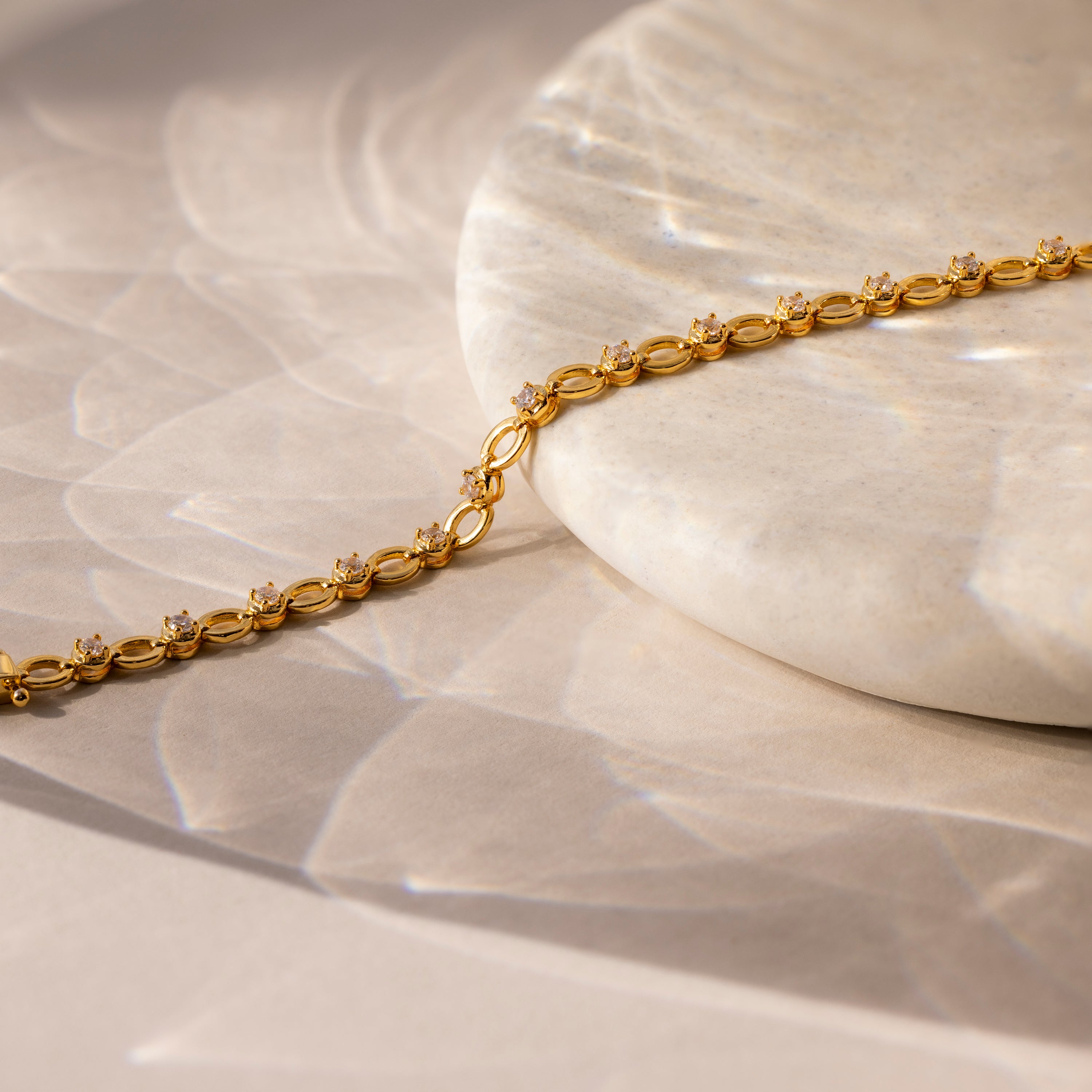 Diamond Chain Tennis Bracelet featuring small diamonds, elegantly displayed on a round marble slab with soft shadows—an enduring piece of jewelry.