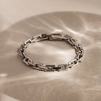 The Eternal Link Bracelet features a sleek geometric design in silver, casting gentle wavy shadows—an ideal modern essential.