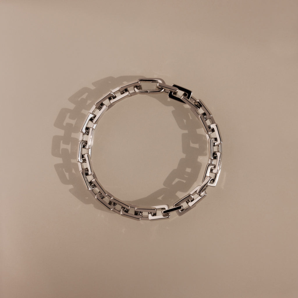 The Eternal Link Bracelet in Silver features rectangular links in a circle on a beige background, highlighting its geometric, modern design.