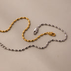 Gold and silver chain necklaces with oval links and clasps, paired with the Oval Beaded Bracelet in 18K Gold, highlight modern jewelry elegance against a neutral background.