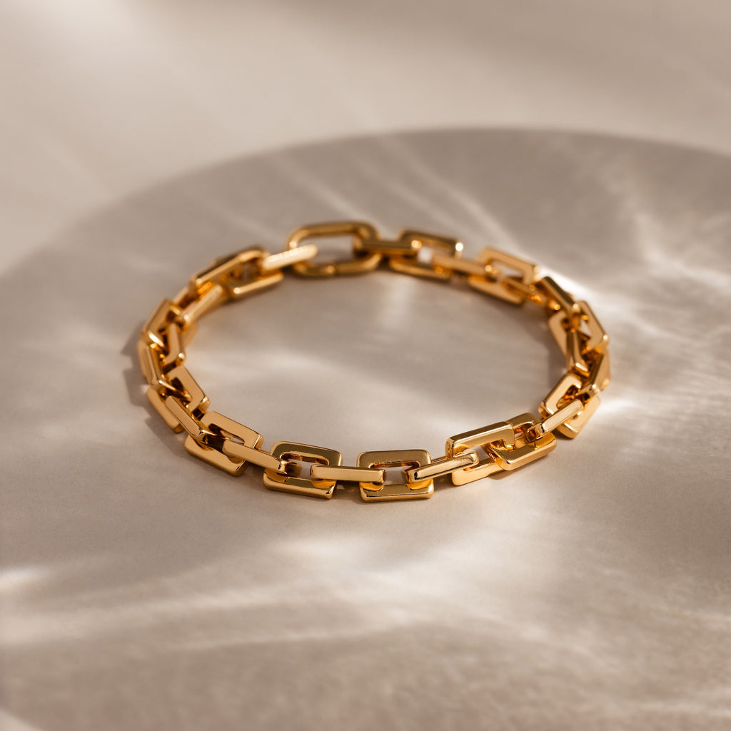 Eternal Link Bracelet in 18K Gold: Features a modern geometric design with rectangular links, presented on a light surface with soft shadows—a must-have contemporary accessory.