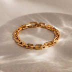 Eternal Link Bracelet in 18K Gold: Features a modern geometric design with rectangular links, presented on a light surface with soft shadows—a must-have contemporary accessory.