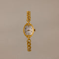 The Heirloom Chain Link Timepiece features a gold band and white oval mother of pearl dial, elegantly showcased on a neutral background.