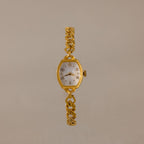 The Heirloom Chain Link Timepiece features a gold band and white oval mother of pearl dial, elegantly showcased on a neutral background.