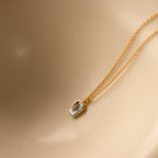 North Star Aquamarine Necklace featuring a rectangular aquamarine crystal pendant displayed on a smooth beige surface.