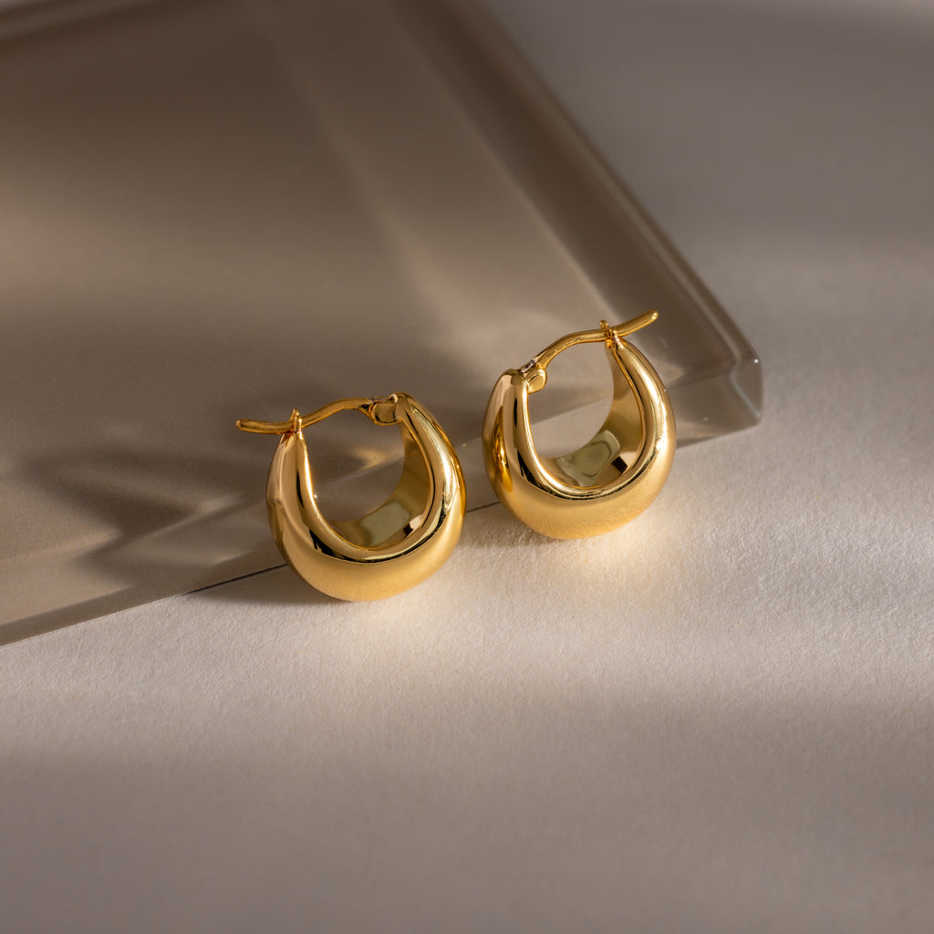 The Bold Teardrop Earrings in 18K Gold feature a chunky silhouette with a high polish finish, showcased on a neutral, softly lit surface.