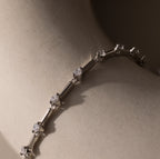 Close-up of the Sprinkle Diamond Tennis Bracelet, featuring delicate round diamonds and elegantly showcased on a smooth, light surface.
