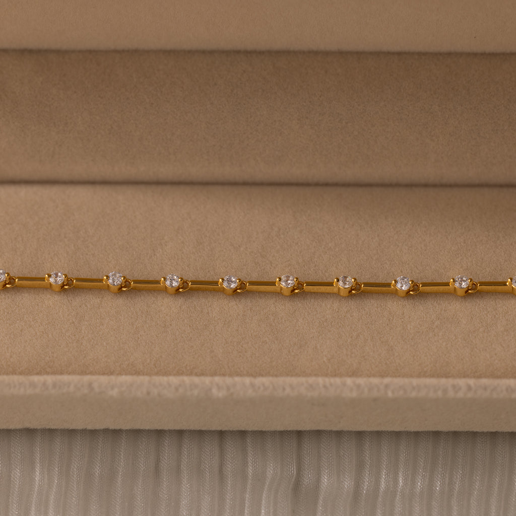 Sprinkle Diamond Tennis Bracelet in 18K Gold, featuring small round diamonds, displayed on a beige velvet jewelry box.