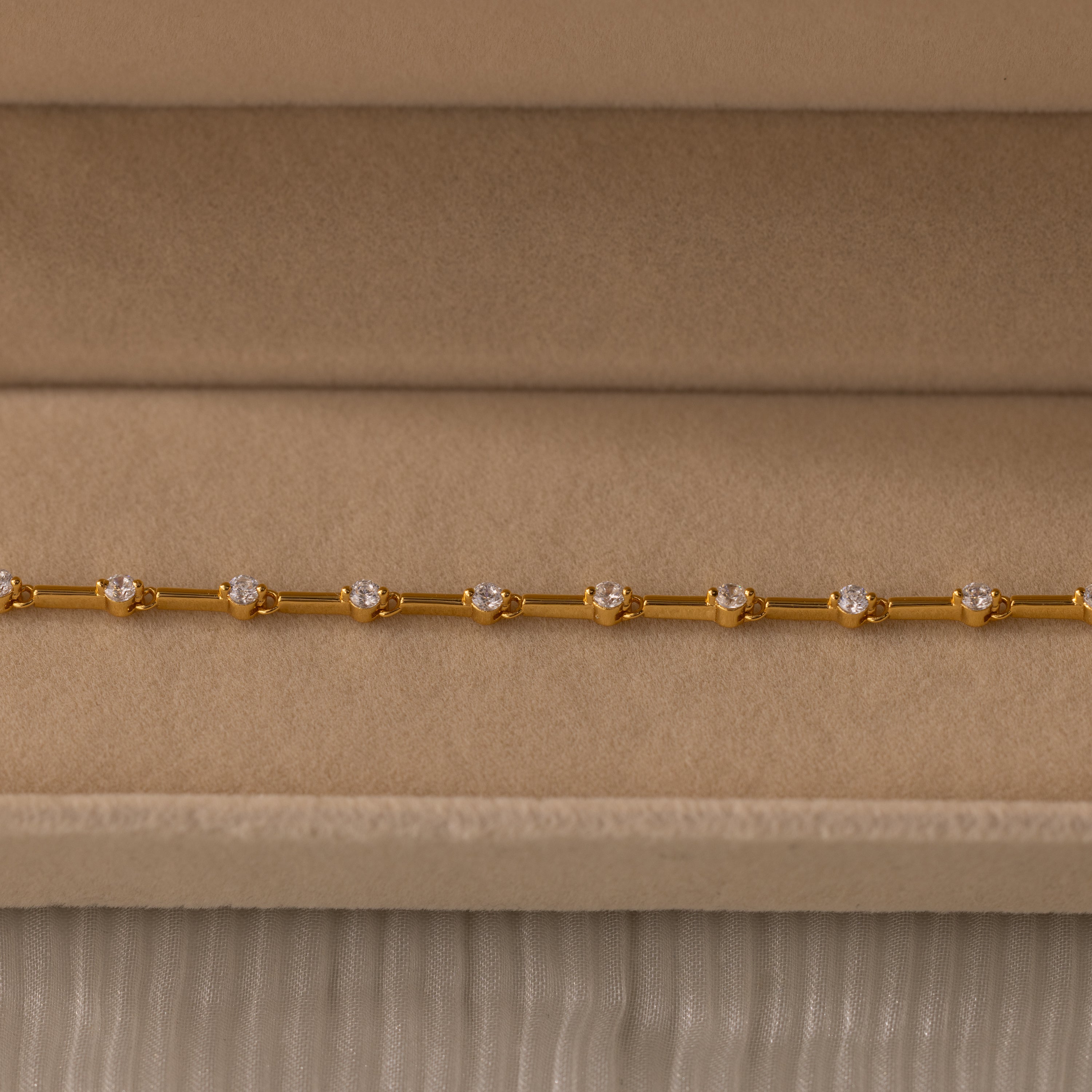 Sprinkle Diamond Tennis Bracelet in 18K Gold, featuring small round diamonds, displayed on a beige velvet jewelry box.