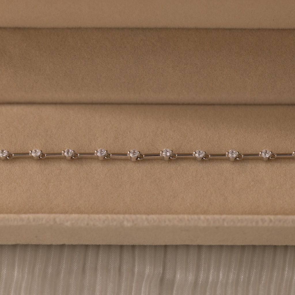 The Sprinkle Diamond Tennis Bracelet in Silver is elegantly displayed in a beige velvet jewelry box.