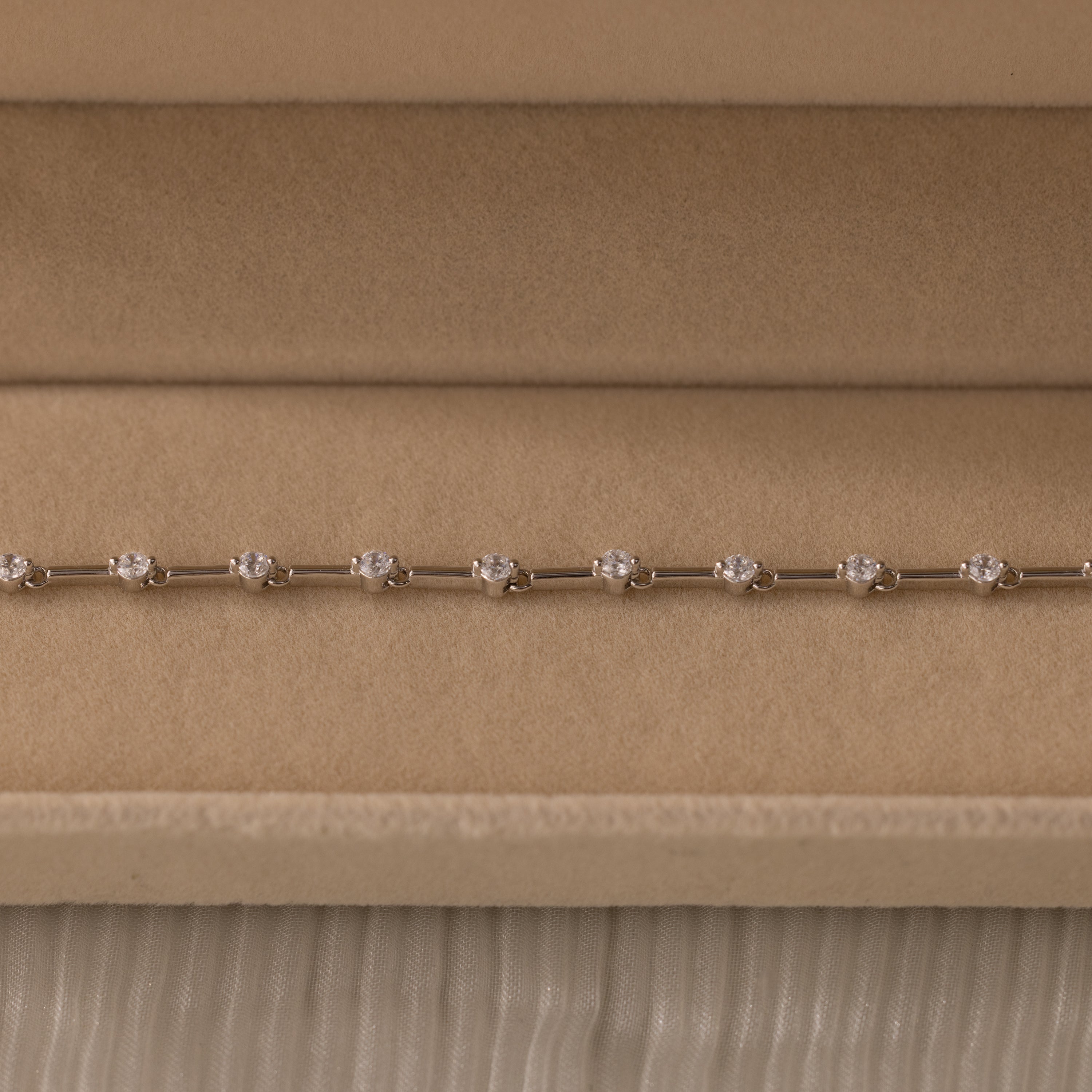 The Sprinkle Diamond Tennis Bracelet in Silver is elegantly displayed in a beige velvet jewelry box.