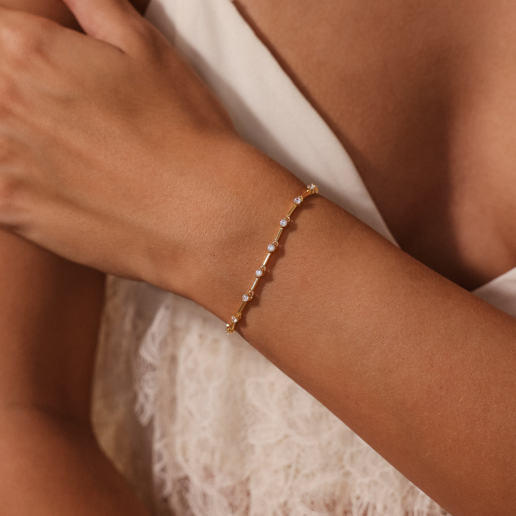 A woman wears the Sprinkle Diamond Tennis Bracelet in 18K Gold on her wrist, paired with a cream lace top.