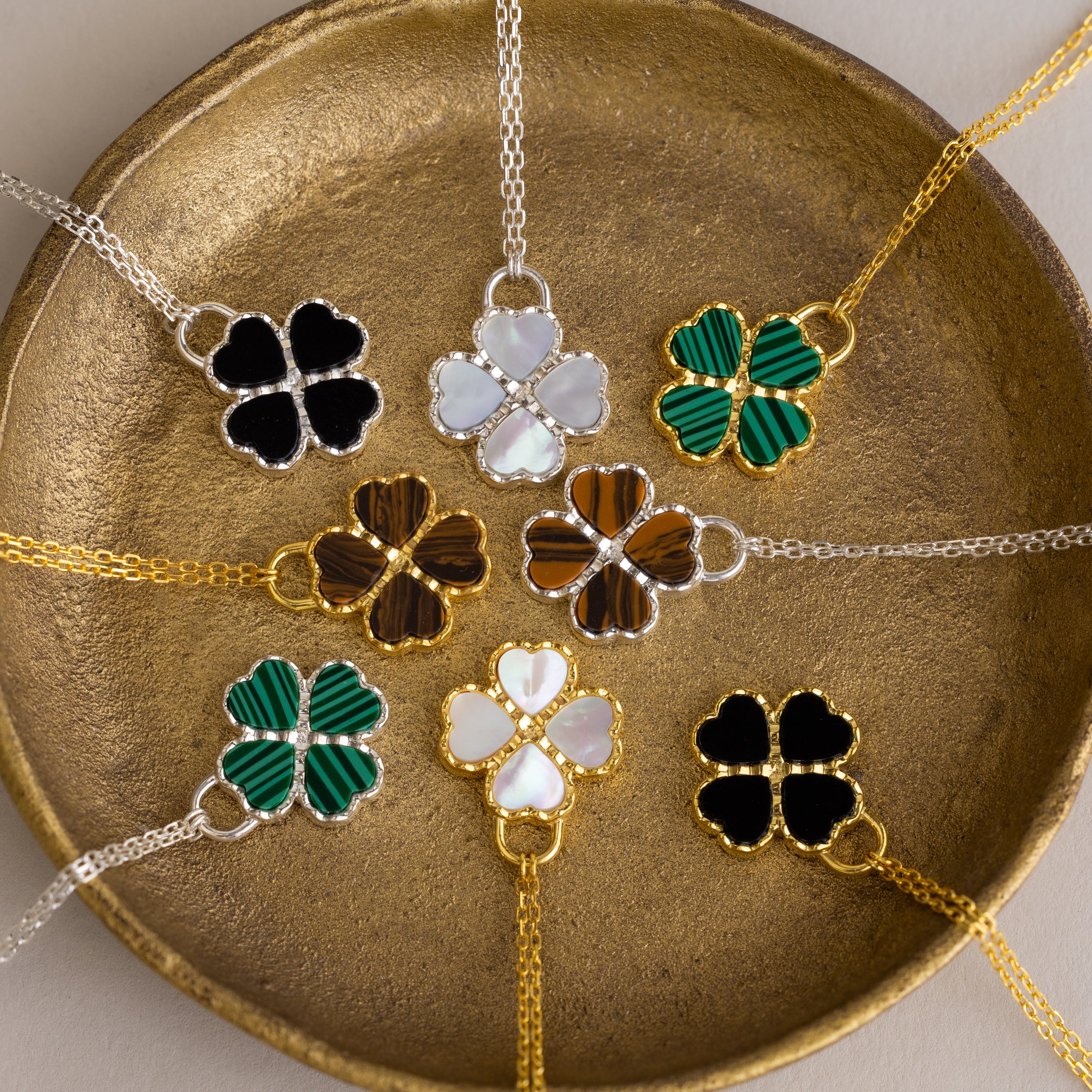 Gemstone Clover Necklaces in gold and silver chains with black onyx, white mother of pearl, green malachite, and brown.