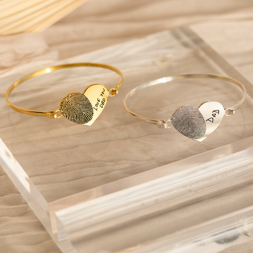 Two Fingerprint Heart Bangles—one gold engraved with "Love you Dad," one silver with "DAD." A heartfelt, personalized jewelry piece capturing his fingerprint forever.