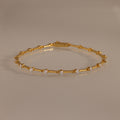 The Sprinkle Diamond Tennis Bracelet in 18K Gold features evenly spaced round diamonds, elegantly displayed on a neutral reflective surface.