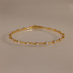The Sprinkle Diamond Tennis Bracelet in 18K Gold features evenly spaced round diamonds, elegantly displayed on a neutral reflective surface.