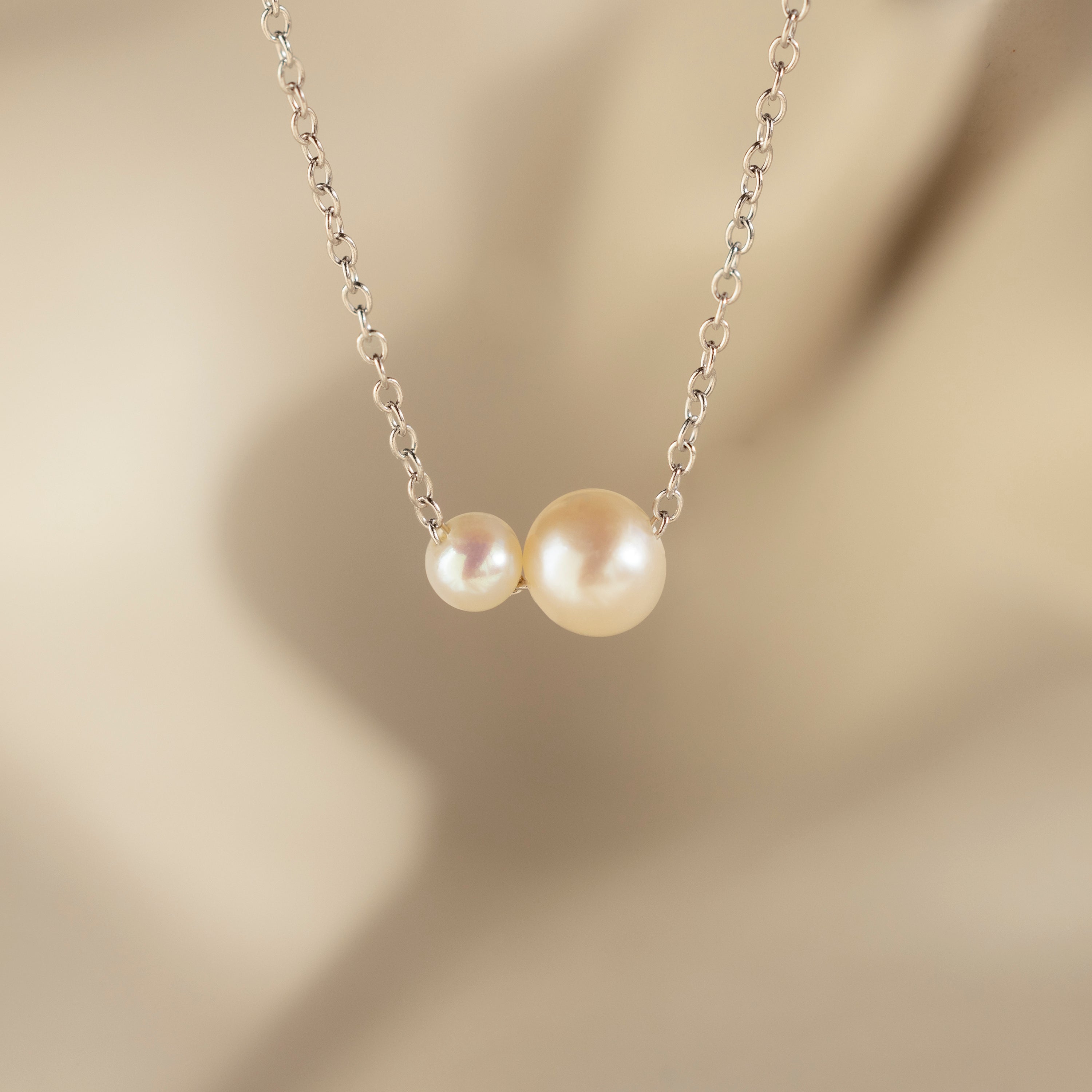 The Dainty Duo Pearl Necklace in Silver features two pearls—a small and a large—on a delicate chain, making it a perfect wedding accessory or thoughtful gift for loved ones.