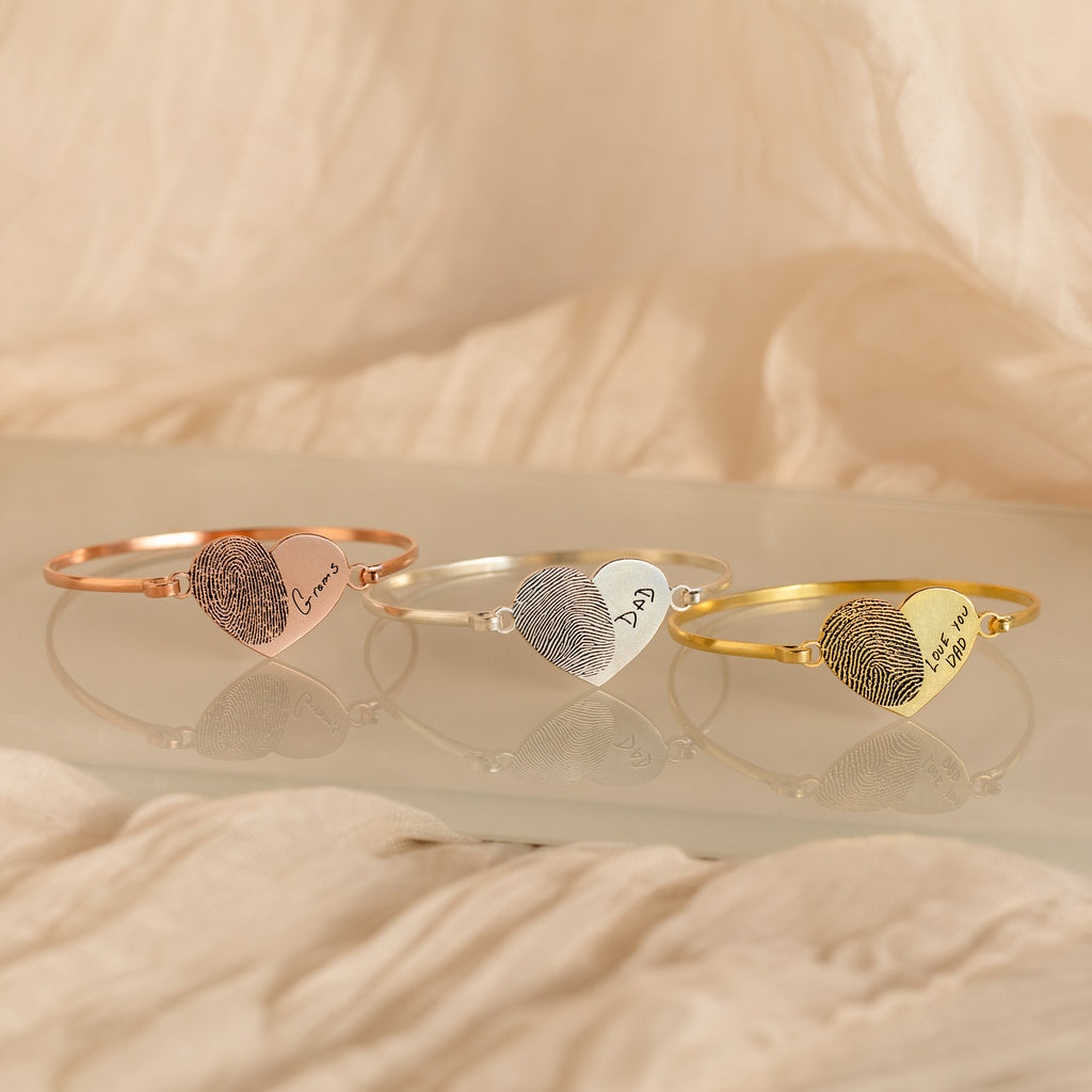 Three Fingerprint Heart Bangles, each engraved with a unique fingerprint and name—Grandma, Dad, and Mom—create beautifully personalized jewelry.