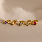 Five pairs of Birthstone Heart Hoops in different gemstone colors laid flat on their side