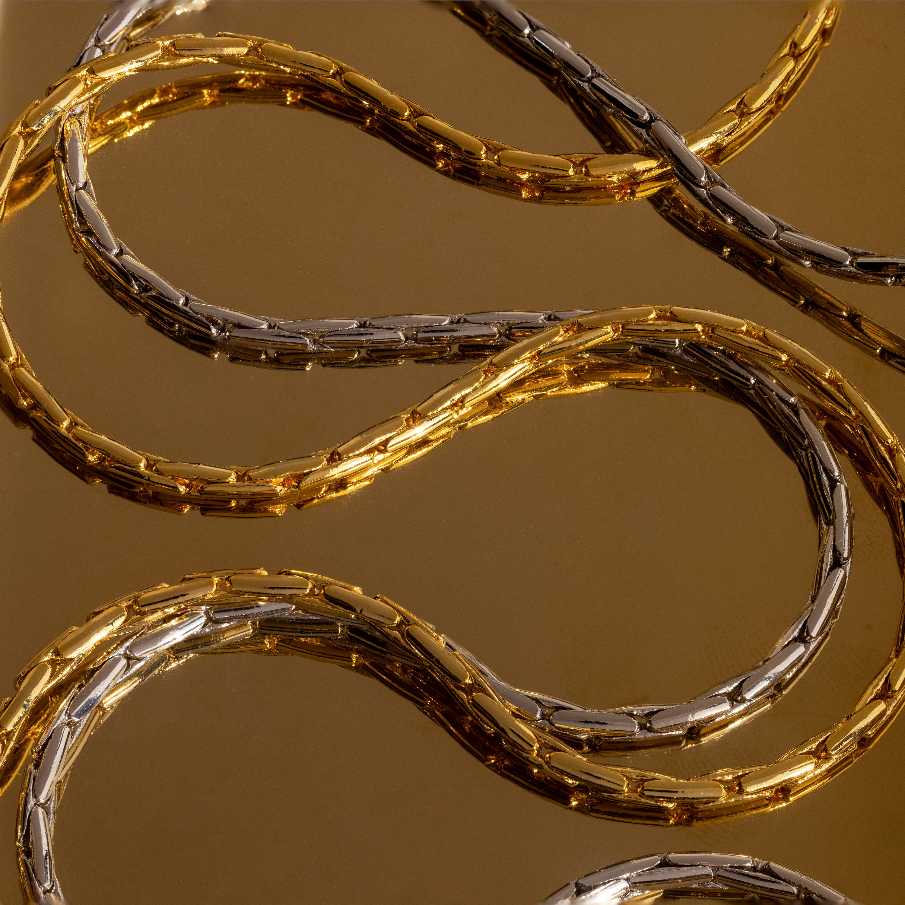 The Bold Link Chain Necklace is displayed on a reflective brown surface, highlighting its striking modern chain style.