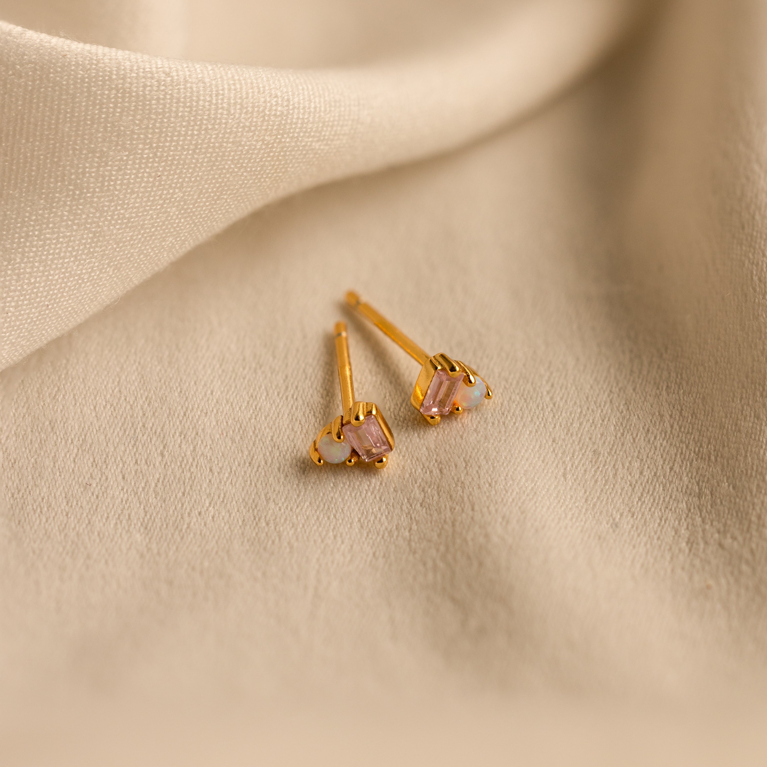 Pink Baguette Opal Studs in 18K Gold displayed on beige fabric with soft folds in the background, perfect as elegant bridal gifts.