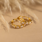 Inside Out Pear Diamond Hoops featuring marquise-cut CZ stones, shown on a beige surface with a softly blurred background.