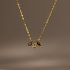 The Multiple Teardrop Birthstone Necklace in 18K Gold features a textured chain with three gemstone pendants—purple, clear teardrop, and green—for a personalized touch to any outfit.