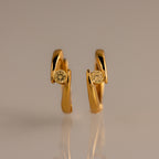Floating Topaz Huggies: Gold hoop earrings with a curved design, each featuring a round yellow topaz at the center, shown on a neutral background.