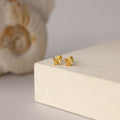 Butterfly Topaz Flatback Studs shown on a cream surface with a decorative shell—ideal as a personalized gift or to add stylish sparkle to any ear stack.