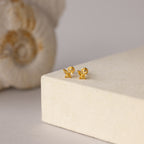 Butterfly Topaz Flatback Studs shown on a cream surface with a decorative shell—ideal as a personalized gift or to add stylish sparkle to any ear stack.