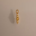 Ombre Lace Topaz Charm: a gold pendant featuring four white gemstones set vertically, displayed on a plain light brown background—an elegant birthstone accessory.
