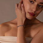 A woman with short hair wears a nude off-shoulder top and the Organic Mariner Chain Bracelet in Silver, touching her face gently for a refined, sculptural look.