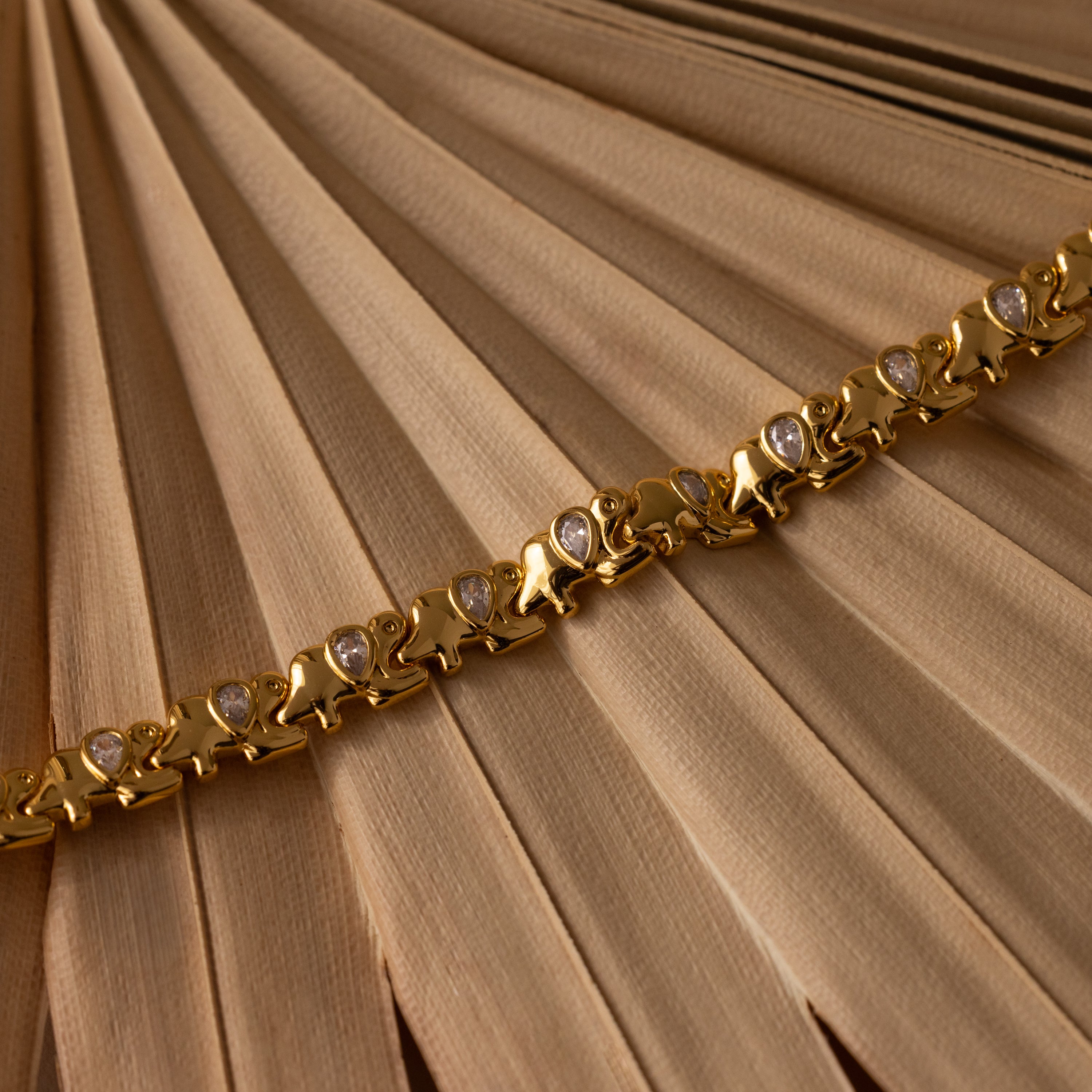 Diamond Elephant Link Bracelet featuring heart-shaped links and small gems, displayed on folded beige fabric.