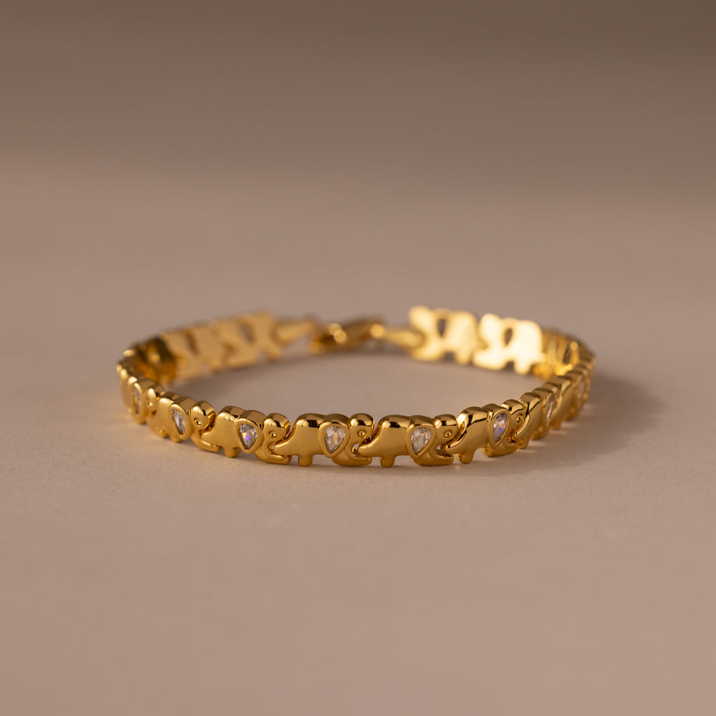 The Diamond Elephant Link Bracelet features a gold design with repeating heart patterns and small diamonds, elegantly displayed on a neutral surface.