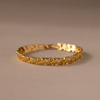 The Diamond Elephant Link Bracelet features a gold design with repeating heart patterns and small diamonds, elegantly displayed on a neutral surface.