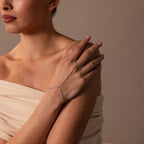 A woman in an off-shoulder top wears the Ocean Beaded Hand Chain Bracelet, a delicate chain adorned with turquoise beads for an elegant look.