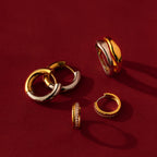The Duo Form Ring Set in Silver is elegantly displayed on a rich red background, capturing sculptural style in gleaming hoops and rings.