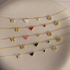 Five gold chain bracelets featuring letter, heart, gemstone, and zodiac charms are displayed on a light stone surface—perfect for pairing with the Dainty Space Charm Necklace or other personalized jewelry for a unique touch.