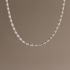 The Beaded Pearl Necklace in White Gold features polished beads displayed against a plain taupe background.