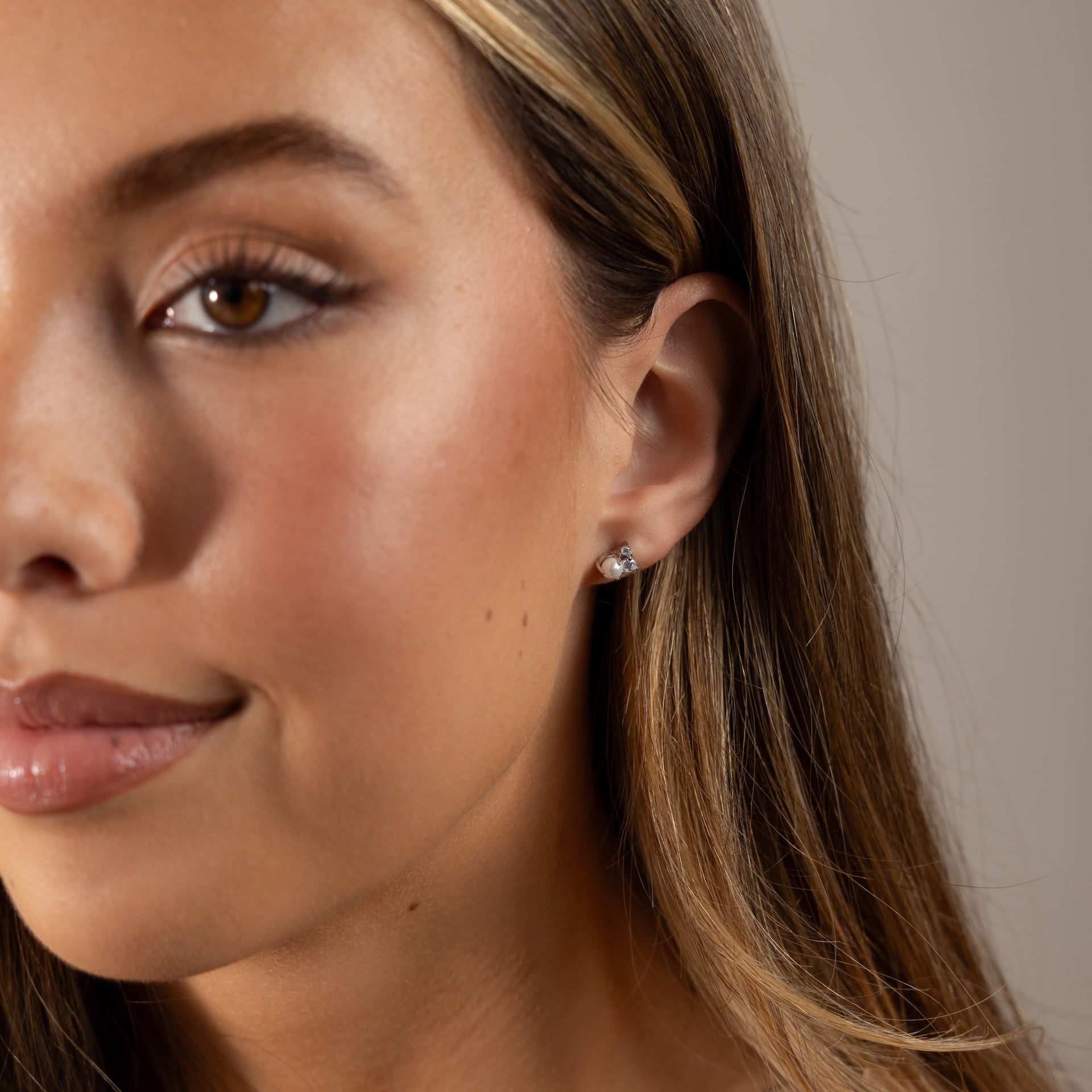 Close-up of a woman with long hair softly smiling, wearing elegant Pearl Diamond Cluster Studs in Sterling Silver.