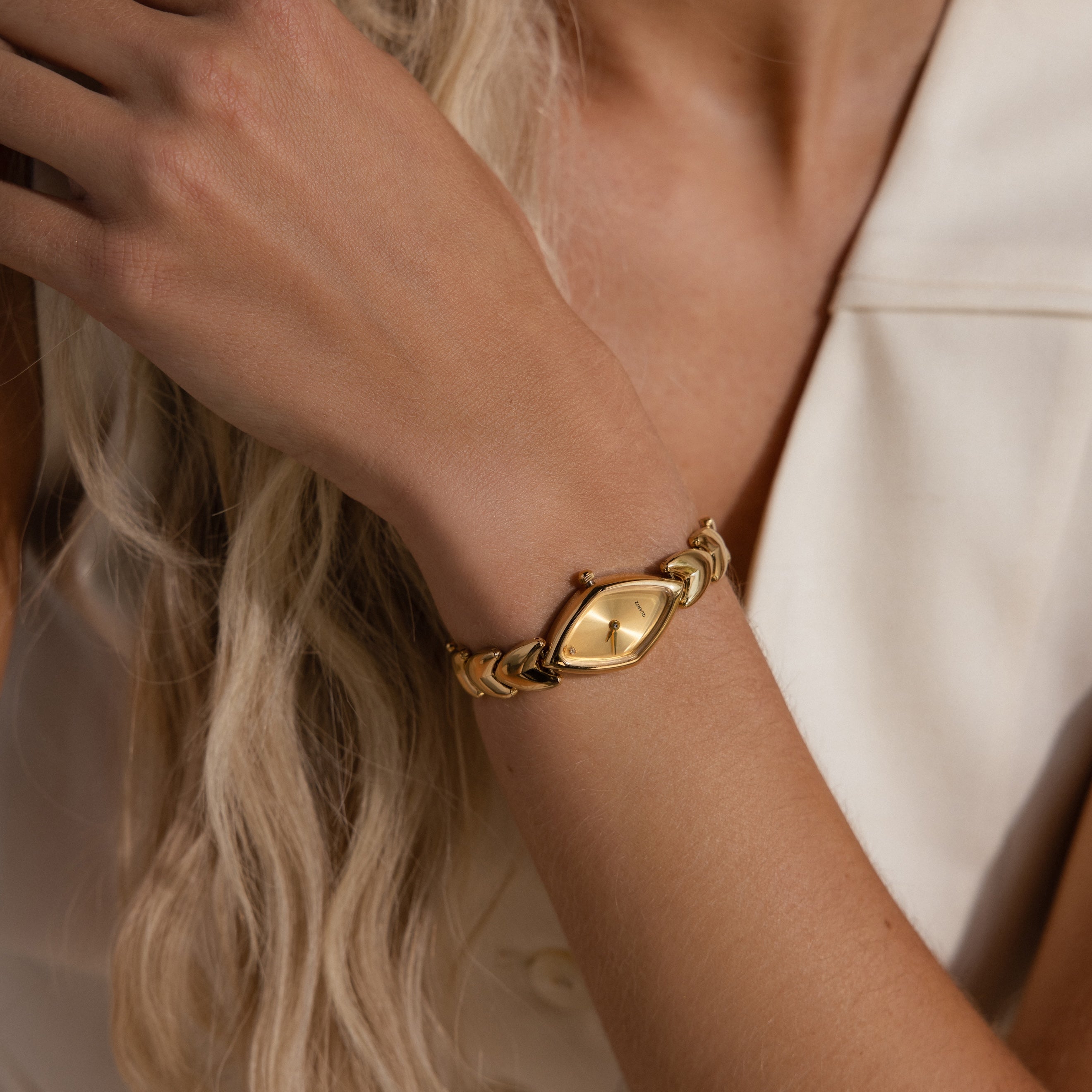 Zoomed-in view of the gold timepiece on a woman's wrist, highlighting the polished links and sleek design.